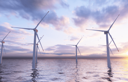 Wind turbines in the sea with the sun low in the sky.