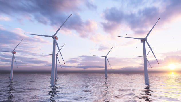 Wind turbines in the sea with the sun low in the sky.