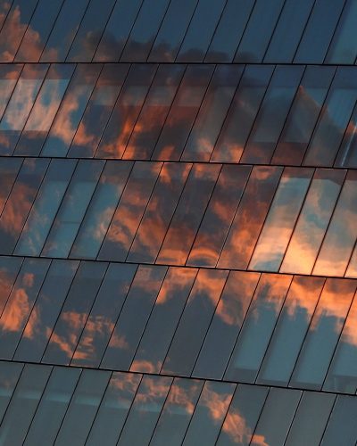 architecture of glass building with reflection of sky sunset